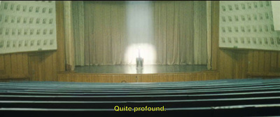 a person standing on a stage in front of a curtain