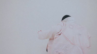 a baby in a pink snowsuit standing in the snow