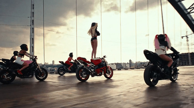 a woman standing on the back of a red motorcycle