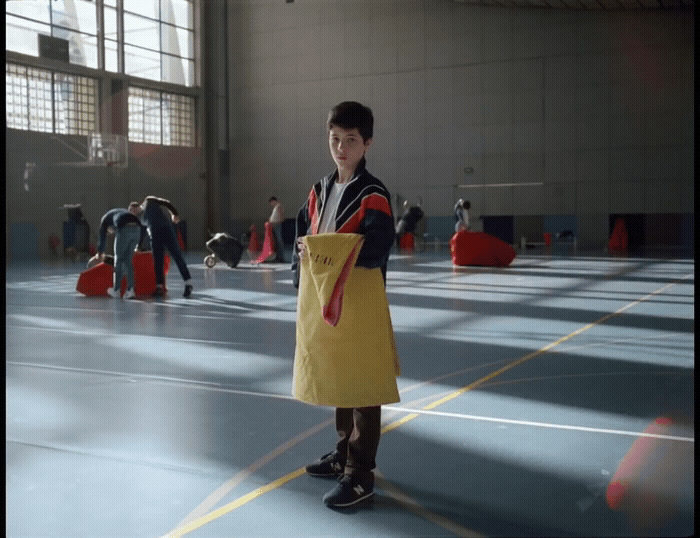 a boy in a gym holding a yellow bag