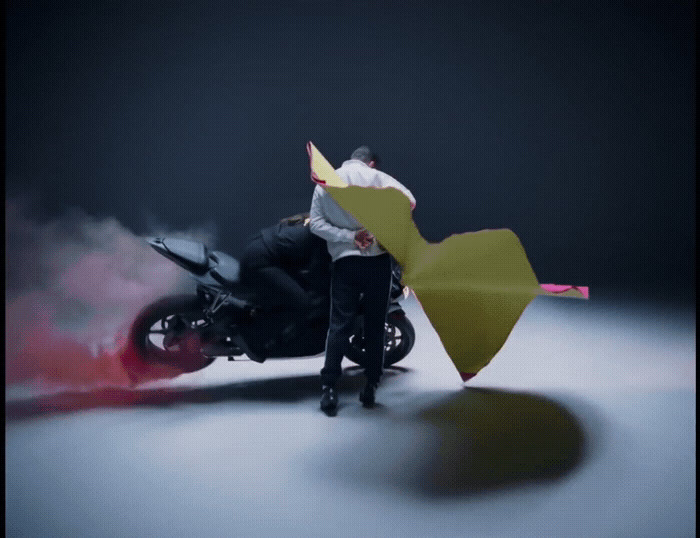 a man riding a motorcycle next to a woman holding an umbrella