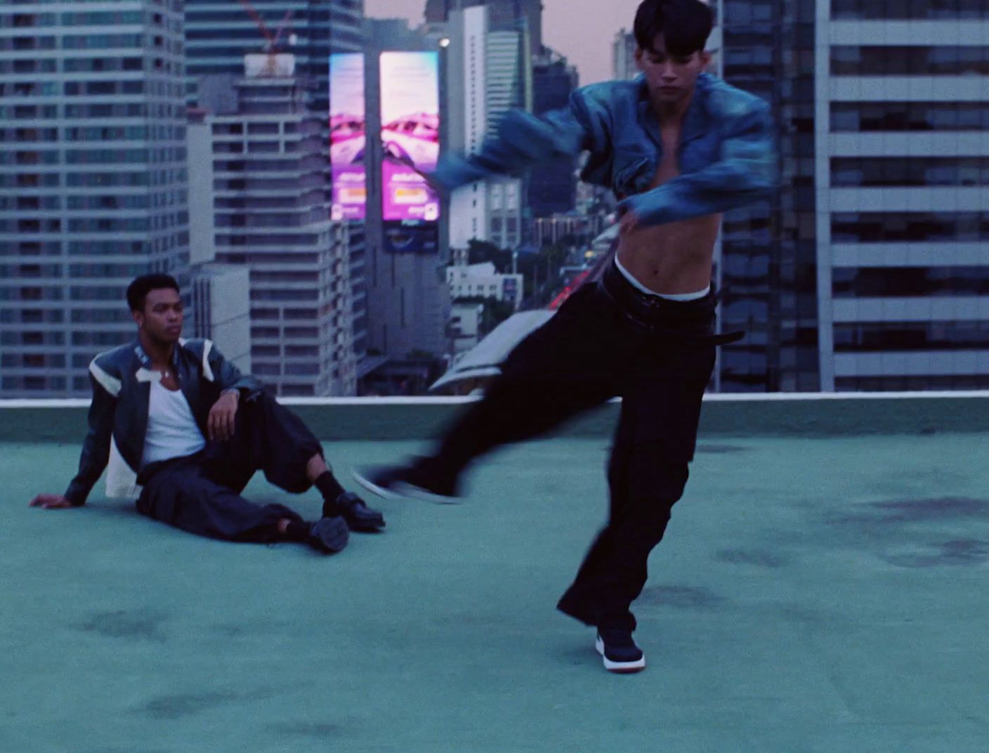 two young men are playing with a skateboard on a roof