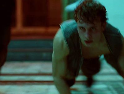 a man in a tank top crouching down on a tile floor