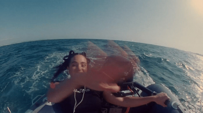 a woman riding on the back of a boat in the ocean