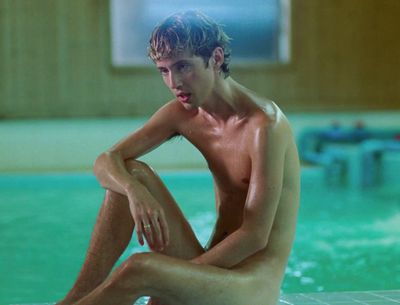 a man sitting on the edge of a swimming pool