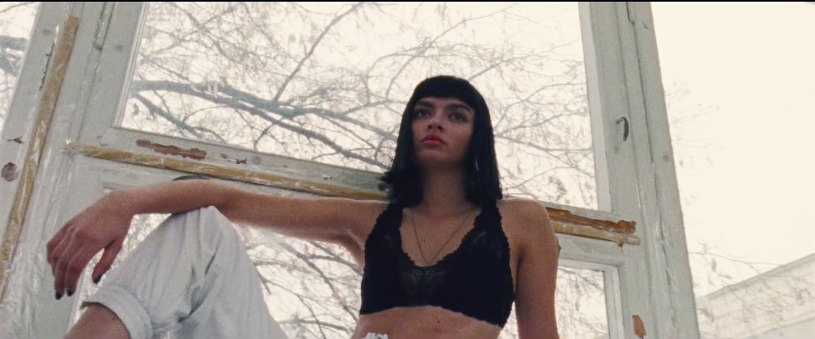 a woman sitting on a window sill in a black top