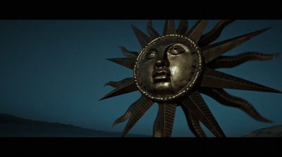 a metal sun face with a blue sky in the background