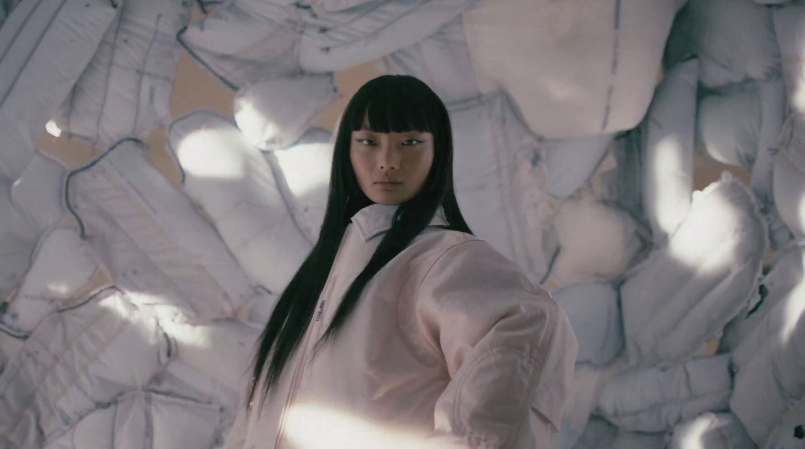 a woman standing in front of a large pile of pillows