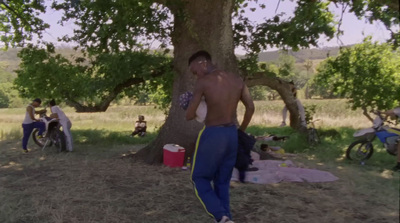 a man standing next to a tree in a field