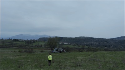 a man standing in a field with mountains in the background