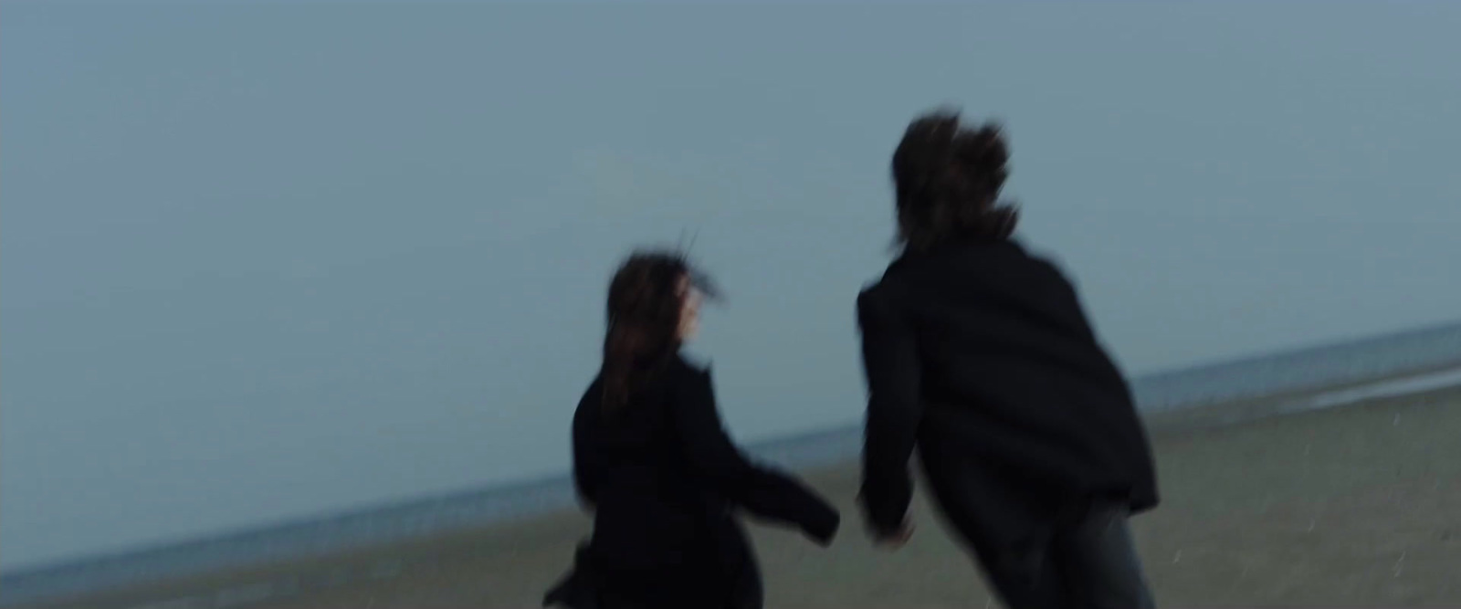 a blurry image of two people walking on the beach