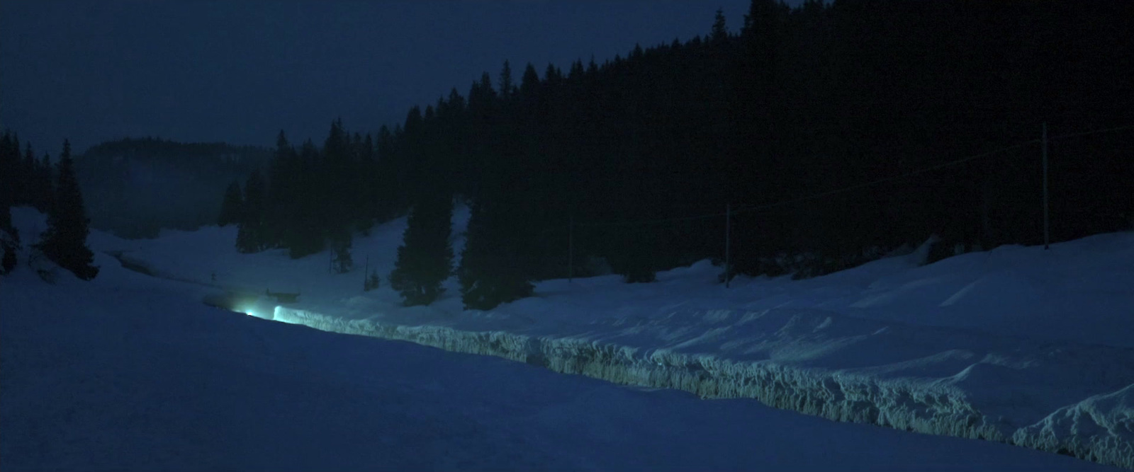 a train traveling through a snow covered forest at night