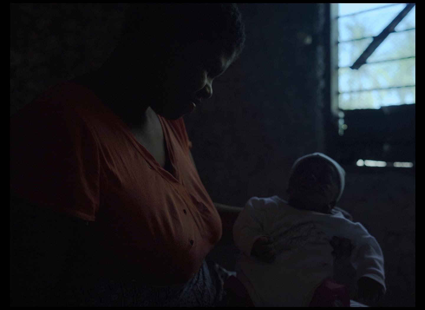 a woman holding a baby in a dark room