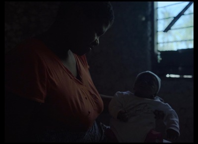 a woman holding a baby in a dark room