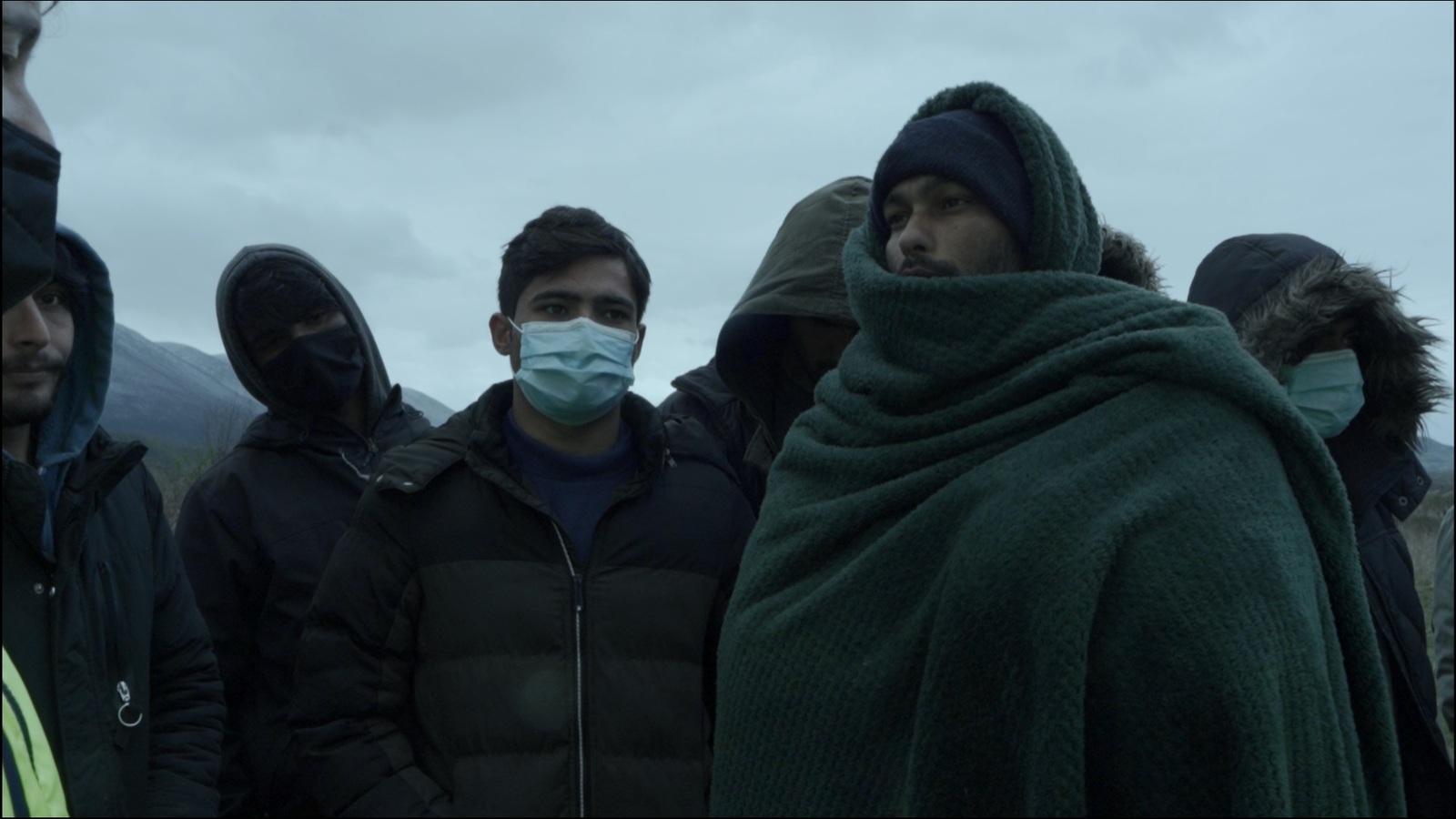 a group of people standing around each other wearing masks