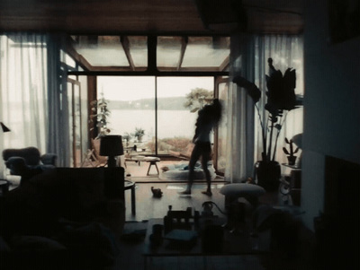 a woman standing in a living room next to a window