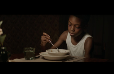 a young girl sitting at a table eating food