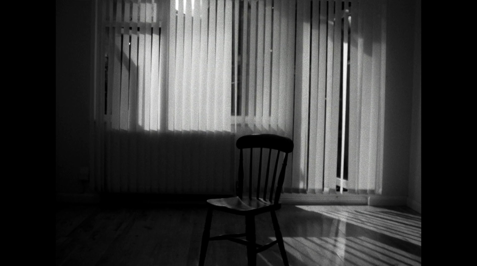 a black and white photo of a chair in front of a window