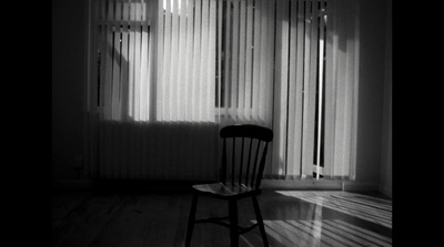 a black and white photo of a chair in front of a window