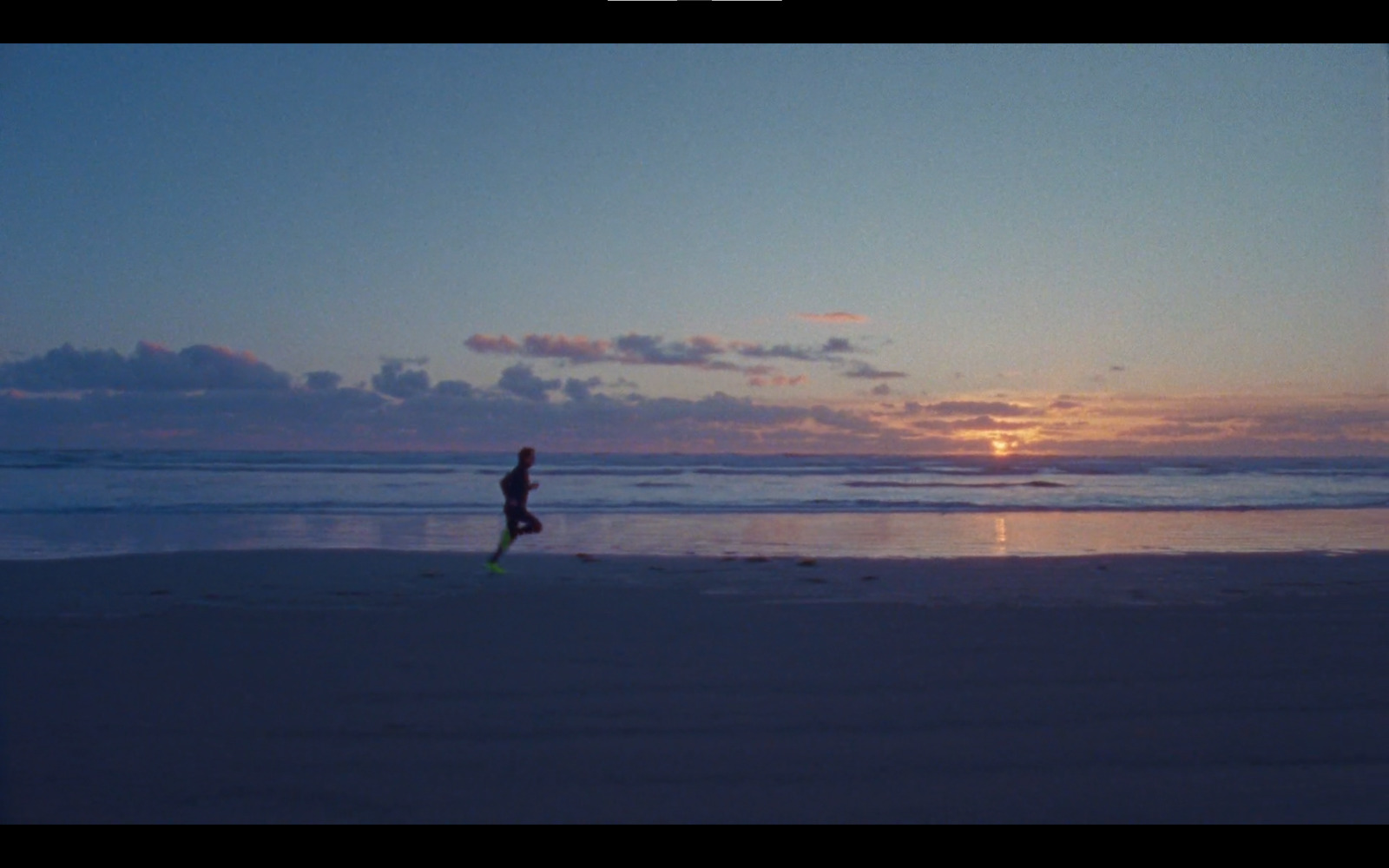 a man running on the beach at sunset