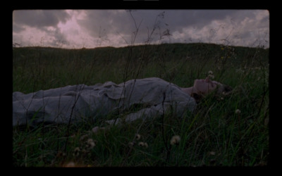 a person laying in a field with a blanket on their back