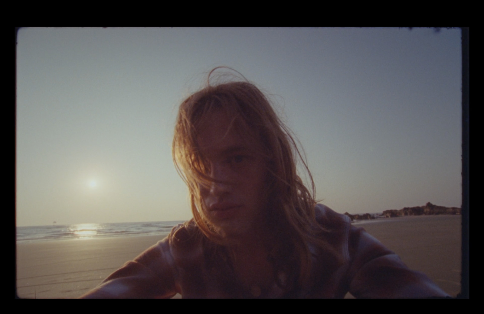 a man with long hair standing on a beach