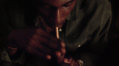 a man smoking a cigarette in a dark room