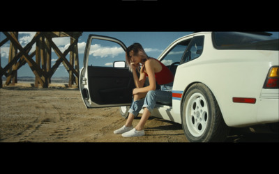 a man sitting on the back of a white car