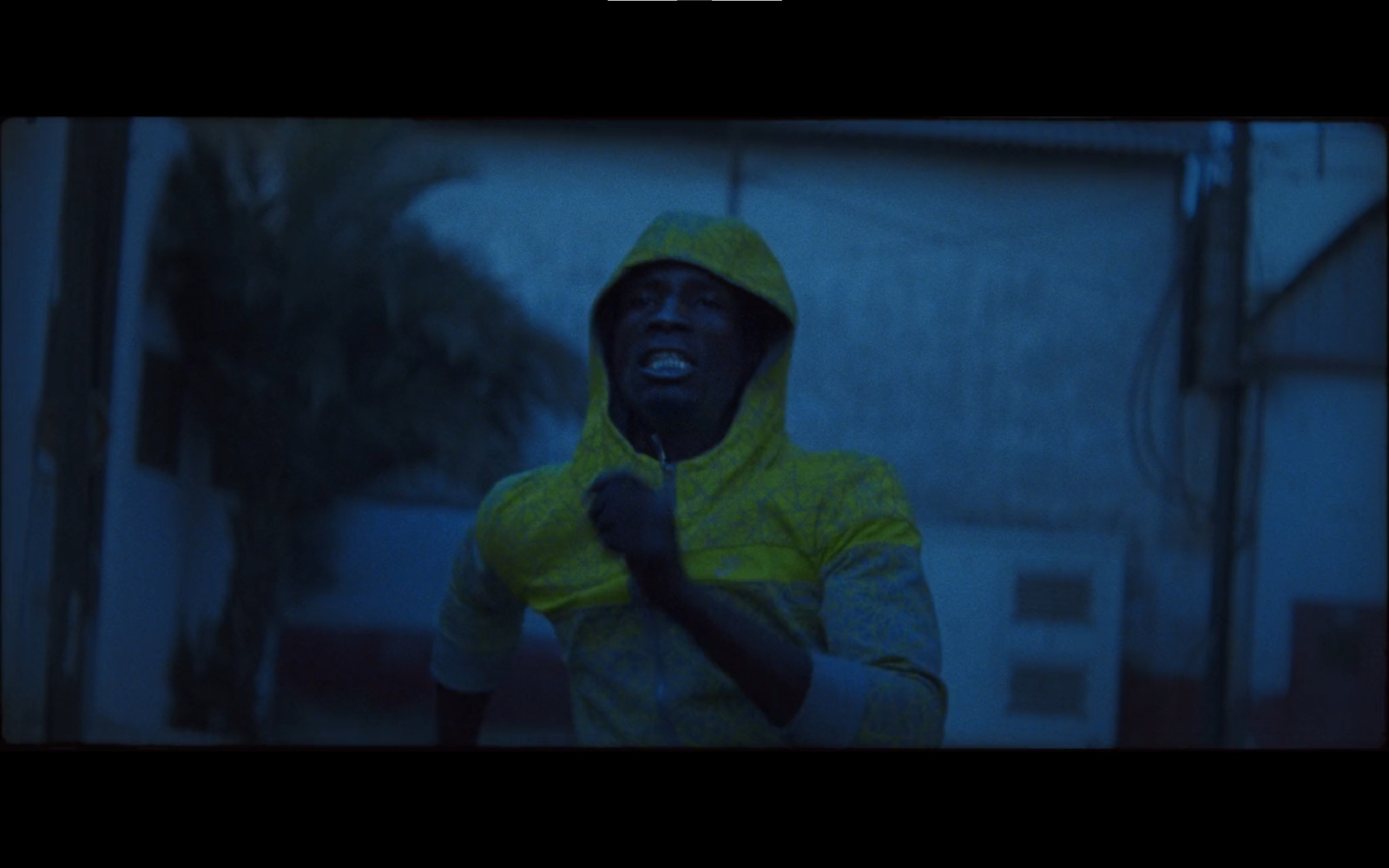 a man in a yellow hoodie is standing in the rain