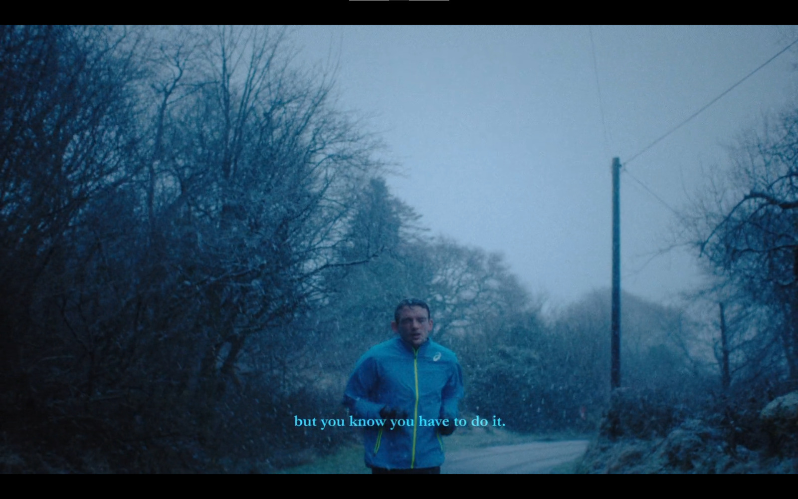 a man in a blue jacket is running in the snow