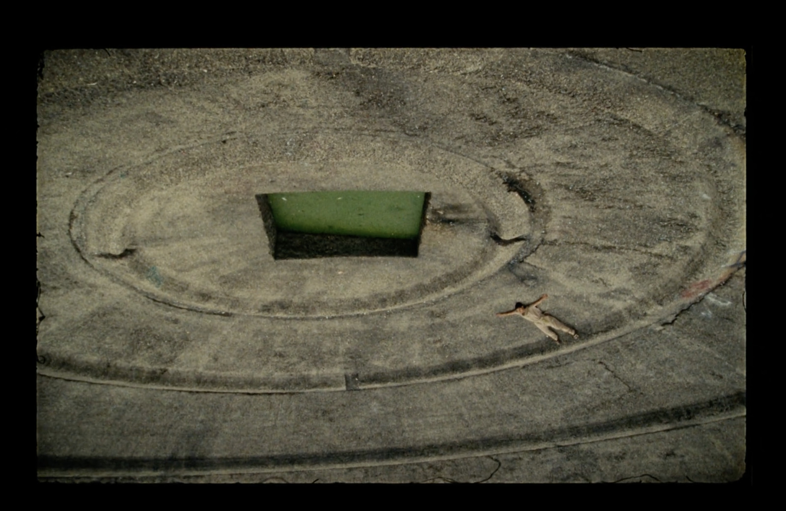 a green bench sitting in the middle of a cement circle