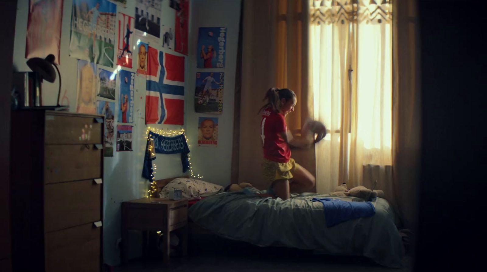 a little girl standing on a bed in a bedroom