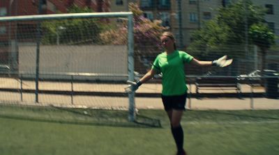 a woman in a green shirt is playing frisbee