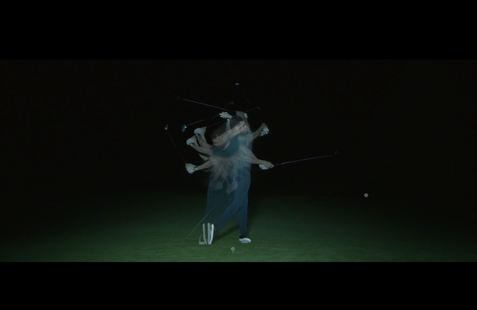 a woman standing in the dark holding a tennis racket