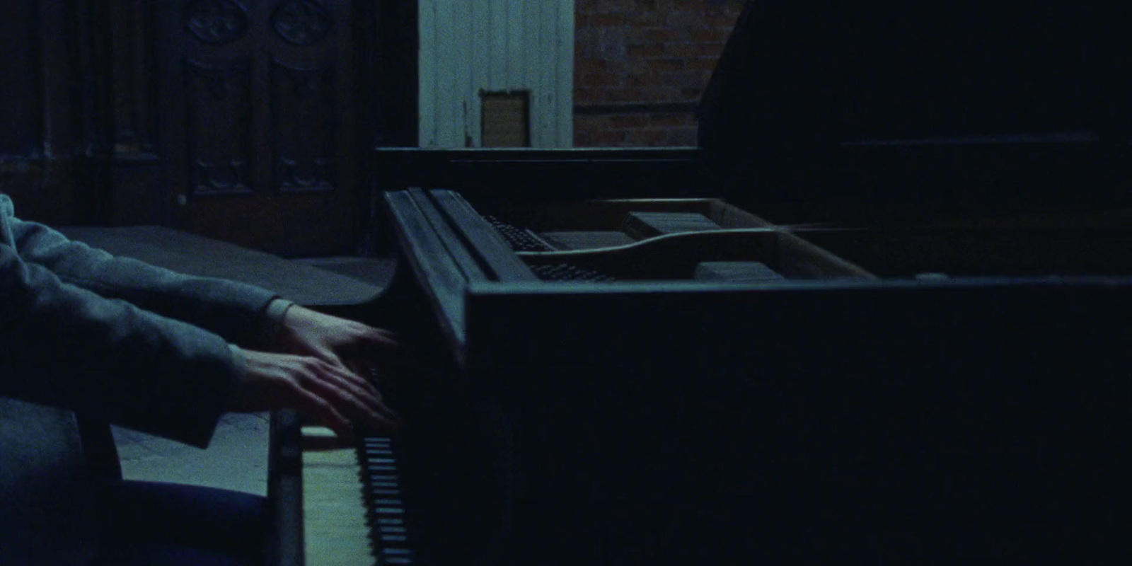 a man sitting at a piano in a dark room