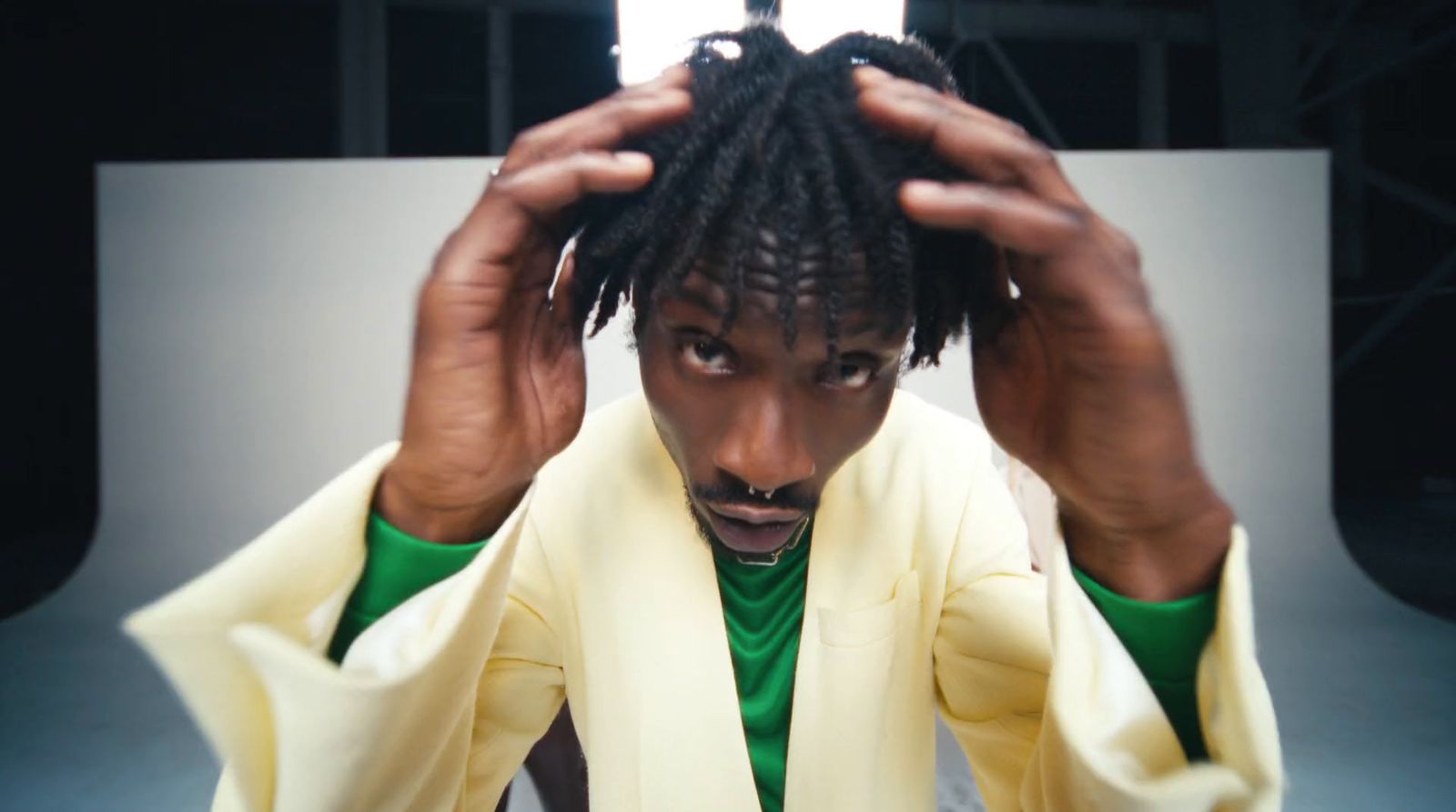 a man with dreadlocks standing in front of a mirror