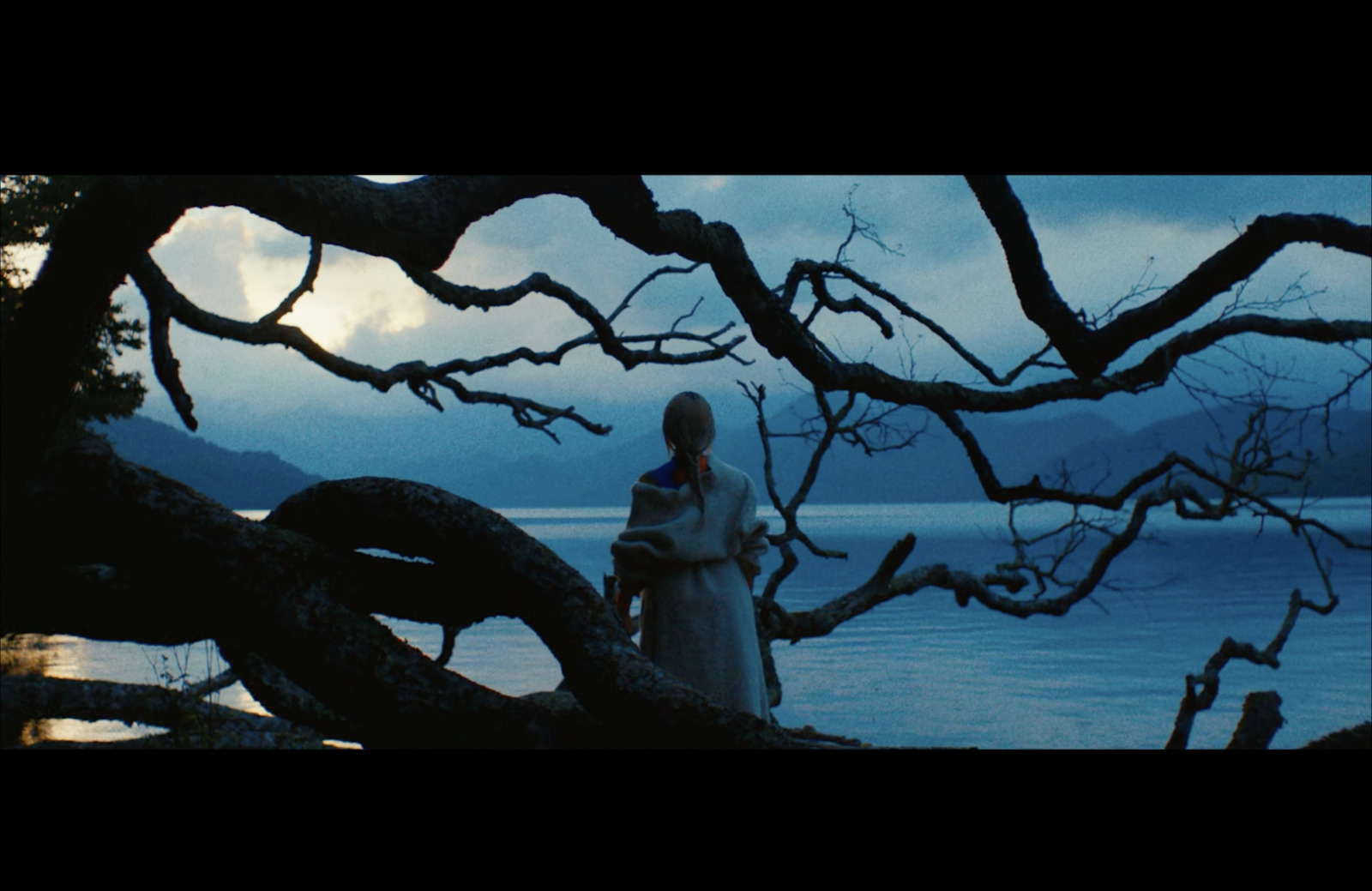 a woman standing next to a tree near a body of water