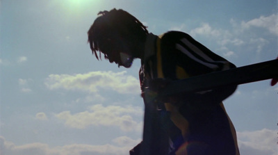 a man holding a skateboard under a blue sky