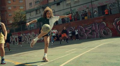 a girl kicking a soccer ball on a court