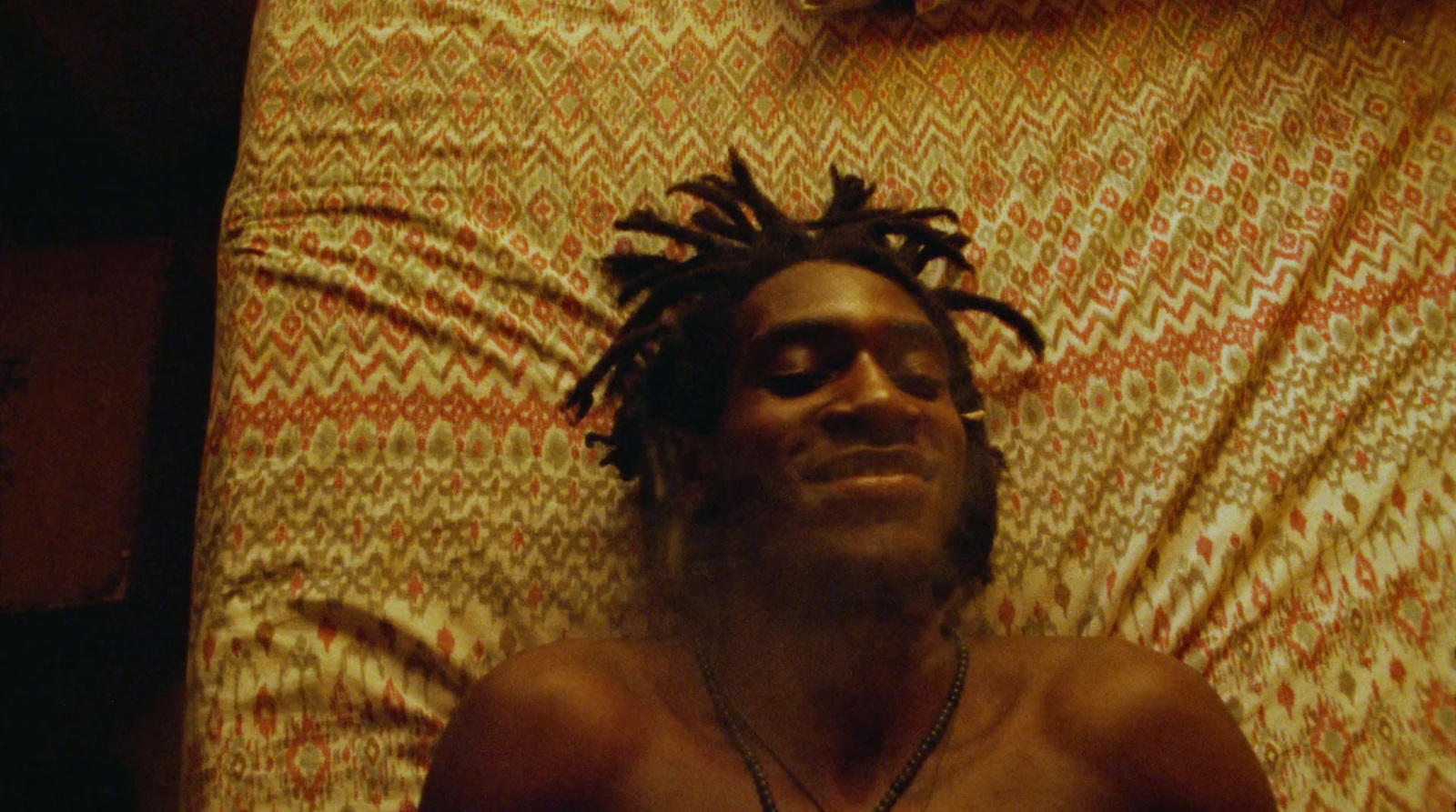 a man with dreadlocks laying on a bed