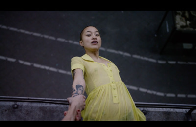 a woman in a yellow dress holding the hand of a man