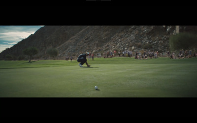 a man kneeling down on top of a green golf field