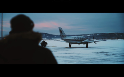 a man standing in front of an airplane on a snowy runway