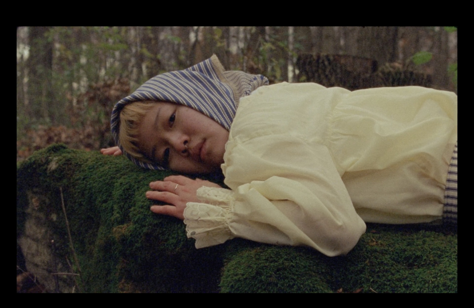 a young boy is sleeping on a mossy log