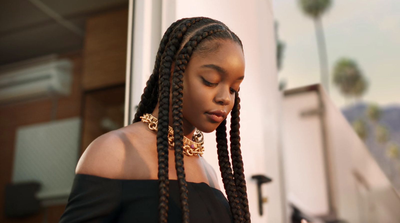 a woman with long braids looking down at her cell phone