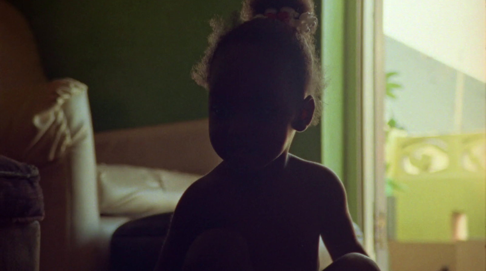 a little girl sitting on a bed in a room