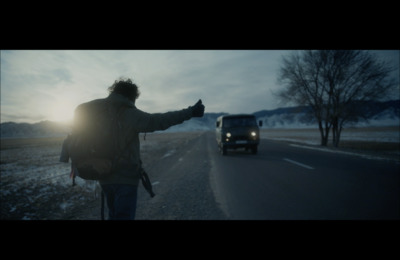 a man standing on the side of a road pointing at a car