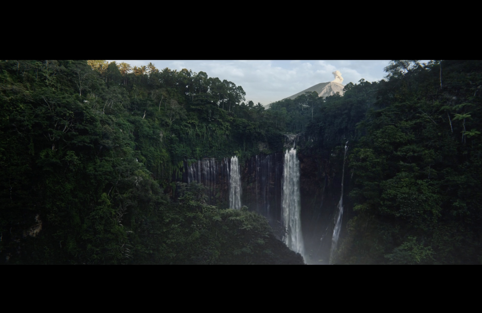 a large waterfall surrounded by lush green trees