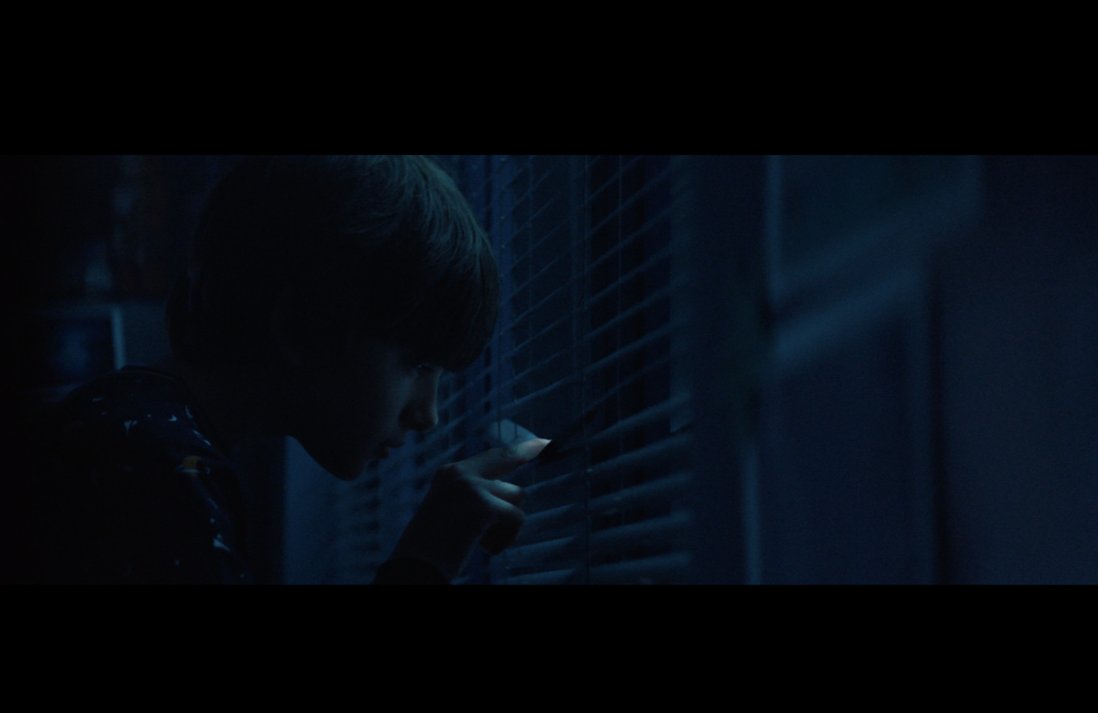 a man standing next to a window holding a cigarette