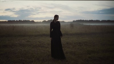 a woman in a long dress standing in a field